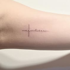 a small cross tattoo on the arm that reads, faith and is written in cursive font