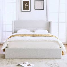 a white bed sitting in a bedroom on top of a hard wood floor next to a window