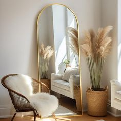 a mirror sitting on top of a wooden floor next to a chair and potted plant