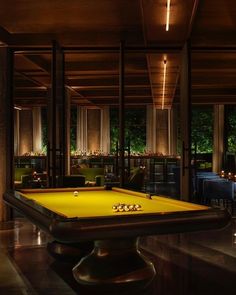 a pool table in the middle of a room with tables and chairs around it at night