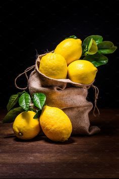 a bag filled with lemons sitting on top of a wooden table