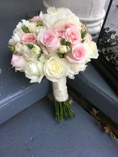 a bouquet of white and pink flowers on a blue door step next to a window