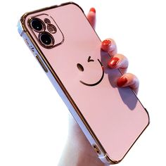 a person holding up a pink phone case with a smiley face on it