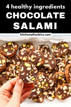 a person holding up a chocolate salami in front of a box of nuts and almonds