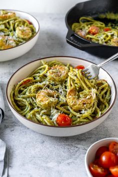 two bowls filled with pesto pasta and tomatoes