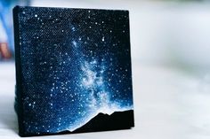 a small canvas with some stars in the sky on it's side, sitting on top of a table