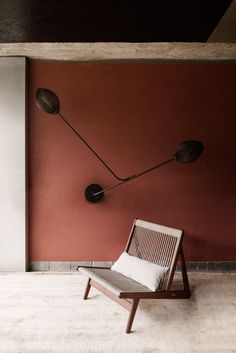 a chair sitting in front of a red wall with two lamps on it's side