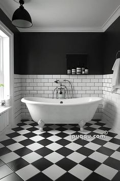 black and white bathroom with checkered tile flooring, claw foot tub and window