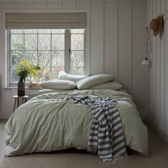 a bed sitting in a bedroom next to a window with a blanket on top of it