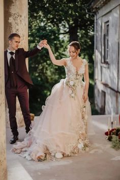 a bride and groom standing in front of an old building with candles on the ground