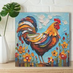 a painting of a rooster on a blue background next to a white vase with flowers