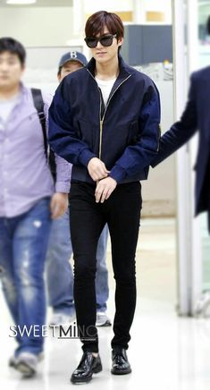 the young man is walking through an airport with his hands in his pockets and wearing sunglasses