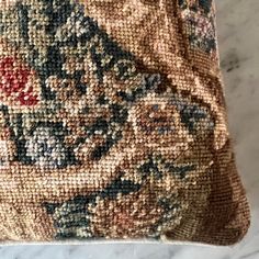 a close up of a decorative pillow on a marble counter top, with an intricate floral design