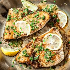 two fish fillets with lemons and chives on a metal plate, ready to be eaten