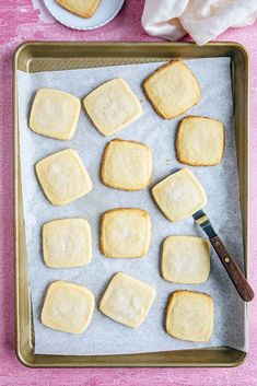 homemade shortbreads on a baking sheet with a knife and napkin next to them