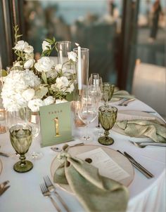 the table is set with white flowers and silverware