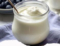 a glass jar filled with yogurt and blueberries