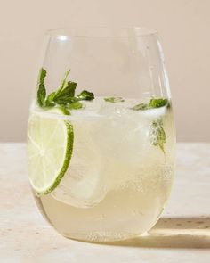 a glass filled with ice and lime on top of a table