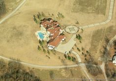 an aerial view of a large house in the middle of a field with a swimming pool