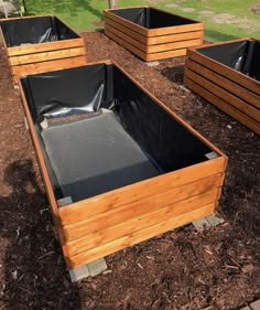 several wooden boxes are lined up on the ground in front of some grass and trees