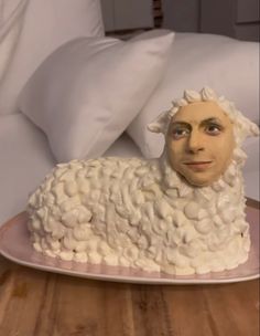 a cake shaped like a sheep sitting on top of a wooden table