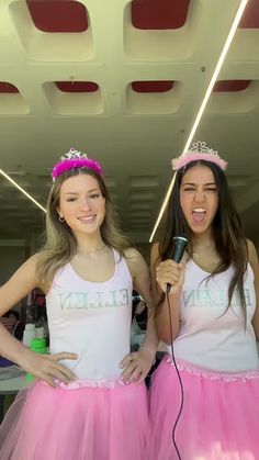 two girls in pink tutu skirts singing into a microphone