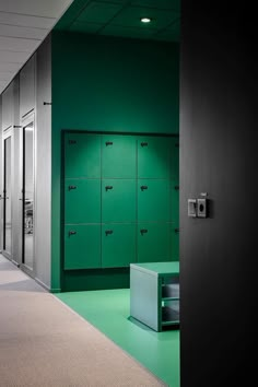 an empty hallway with green lockers on the wall and carpeted flooring in front of it