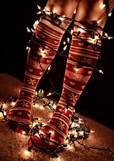 a woman's legs with christmas lights on them and stockings wrapped around her ankles