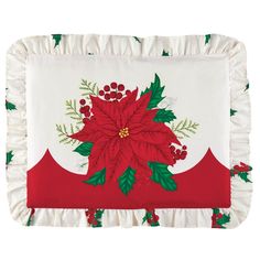 a red and white poinsettia pillow with green leaves on the bottom, surrounded by holly