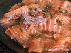 a close up of a plate of food with fish on it's side and garnished with herbs