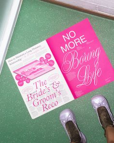 there is a pink book on the floor next to someone's feet and shoes