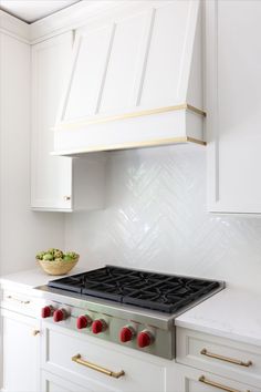 White kitchen with white wood cabinetry hood trimmed in gold accents Gold And White Range Hood, Hood Vent Cover, Wood Range Hood, White Range, Green Island