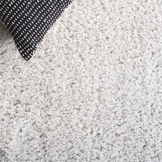 a black and white pillow sitting on top of a carpeted floor next to a bed