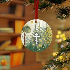 a christmas ornament with a cross on it hanging from a tree in front of a bookshelf