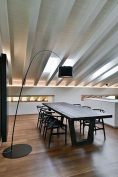 an empty dining room with wooden floors and white walls is pictured in this image, there are several black chairs around the table