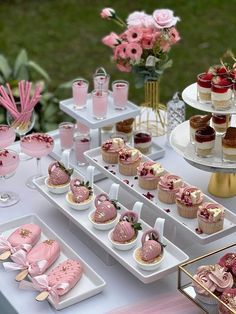 a table topped with cakes and desserts on top of white plates covered in pink frosting