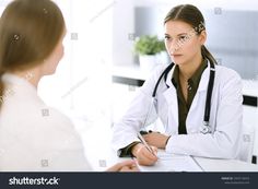 a doctor talking to a patient in her office at the desk with a clipboard