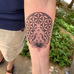 a man's leg with a flower of life tattoo on his left arm and an elephant in the middle