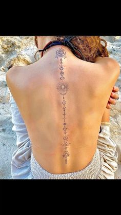 the back of a woman's body with tattoos on her upper and lower back