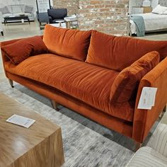 an orange couch sitting on top of a carpeted floor next to a brick wall