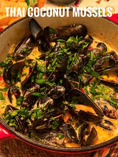 a pot filled with mussels and greens on top of a table