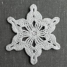 a white crocheted snowflake sitting on top of a gray table cloth