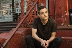 a man is sitting on the steps in front of an old building with red paint