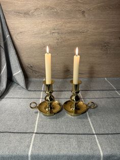 two candles are sitting next to each other on a bed