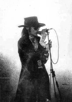 an old photo of a man in a top hat and coat singing into a microphone