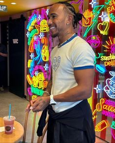 a man standing in front of a table with a cake on it and a neon sign behind him