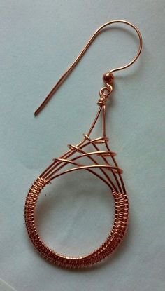 a pair of copper wire earrings on top of a white surface with a blue background