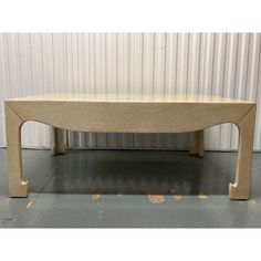 a large wooden table sitting in front of a white metal wall with no one on it