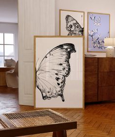 two framed pictures sitting on top of a hard wood floor next to a wooden table