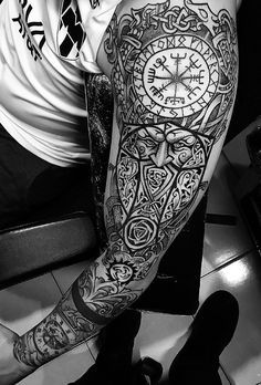 black and white photograph of a man with tattoos on his arm, holding a clock